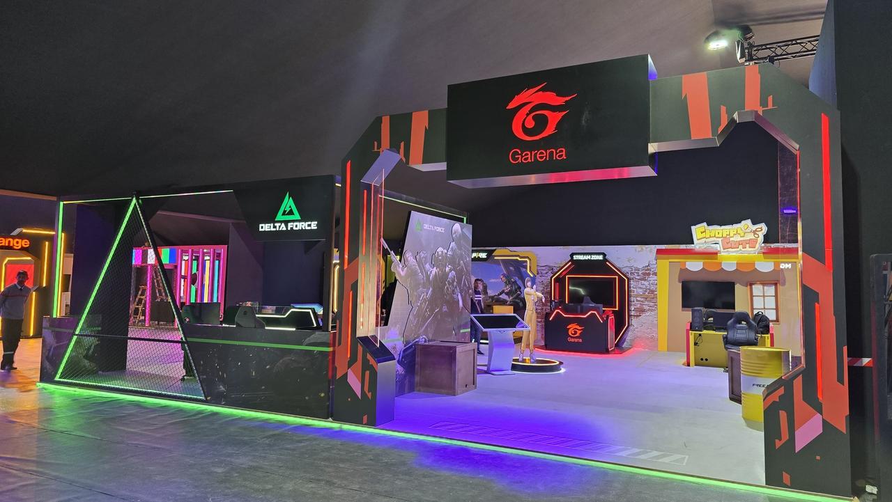 Stand Garena livré, de nuit : arche lumineuse et enseigne Garena, triangle lumineux de la zone Delta Force.