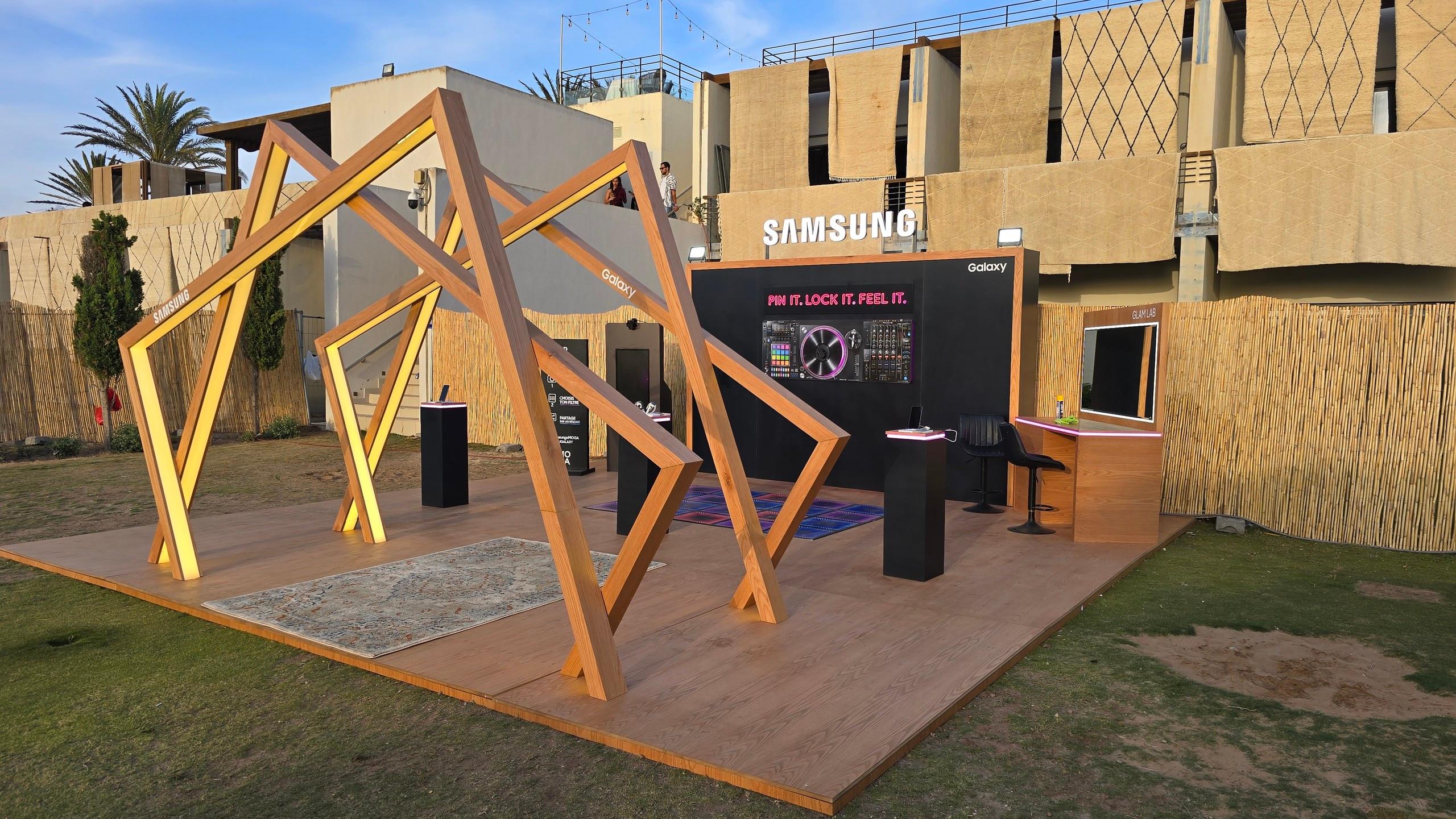 Le stand Samsung Galaxy livré, de jour : plancher bois, arches lumineuses et mur de marque.