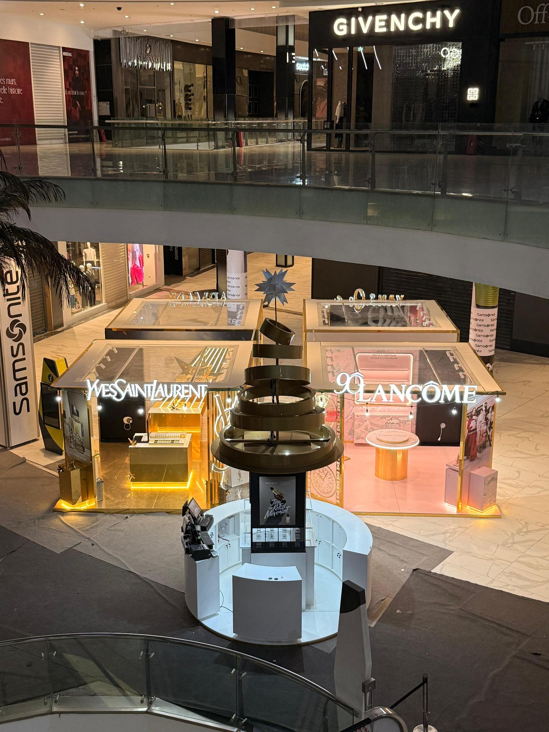 Le village livré, de nuit : quatre cabines dorées autour d’un kiosque central, dans l’atrium.